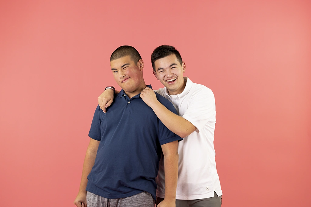 Two teenage boys smiling hugging