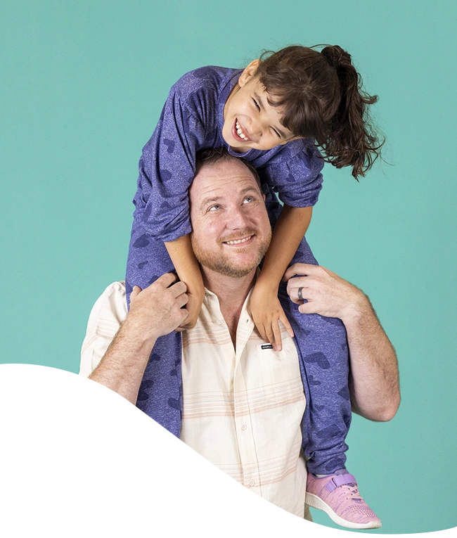 Daughter sitting on father's shoulder laughing